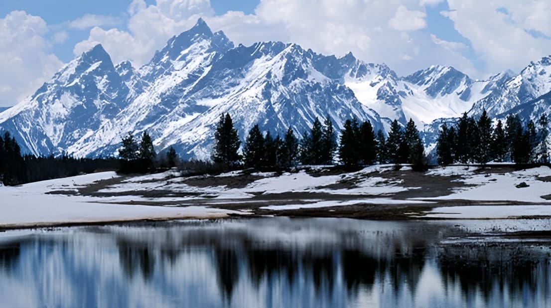 Snowy mountains reflected in calm lake